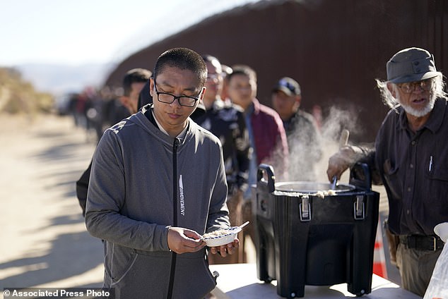 A man from China receives a bowl of oatmeal from a volunteer as he waits with others to be processed to claim asylum after crossing the U.S. border with Mexico