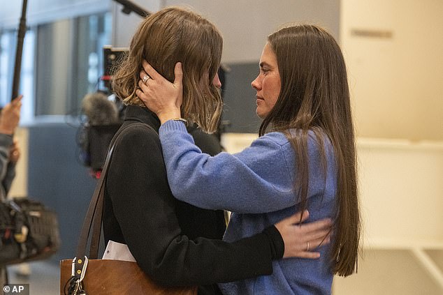 Caitlin Cash (right) hugs Mo Wilson's family members during the trial of the cyclist's alleged killer