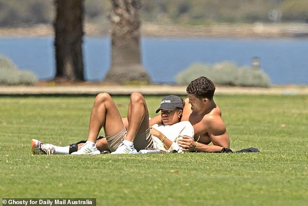 The NRL superstar and football sensation were spotted wearing matching bracelets as they lay side by side on the lush grass