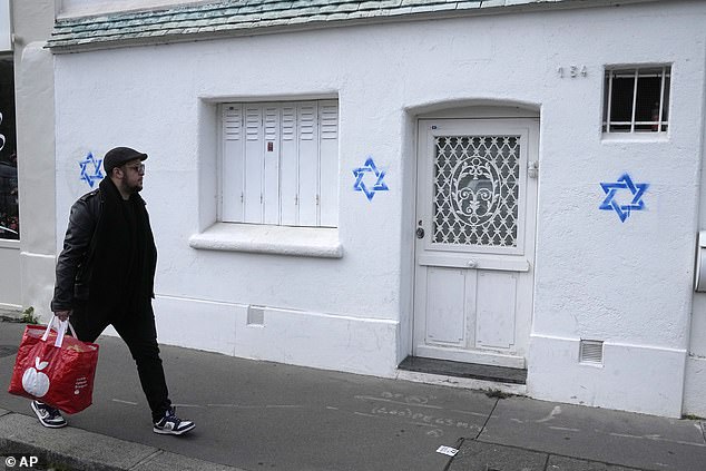 A man walks past Stars of David tagged on a wall in Paris on Tuesday, October 31, 2023.  Paris police chief Laurent Nunez described the graffiti as anti-Semitic and said police were investigating