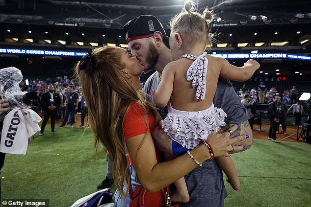 Jonah Heim kisses his wife Kenzie and holds their daughter in his arms after the win