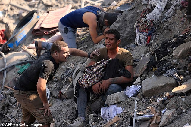 A man cries as he holds his mother's remains wrapped in a blanket, amid the rubble of a building destroyed during an Israeli attack on the Bureij refugee camp, November 2