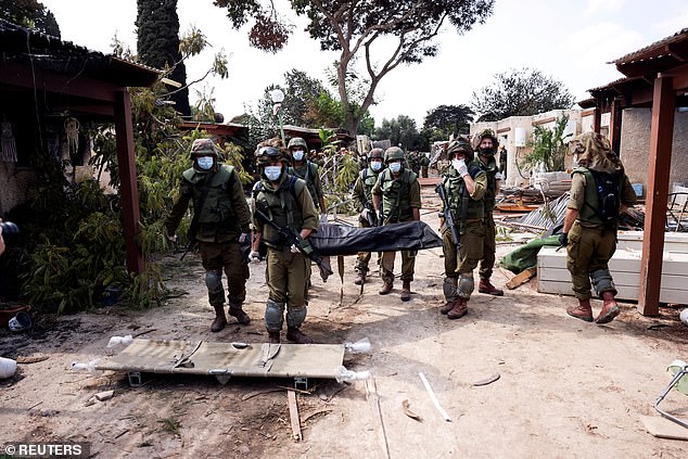 Israeli soldiers carry the body of a victim of an attack by Gaza militants in Kibbutz Kfar Aza, southern Israel, October 10