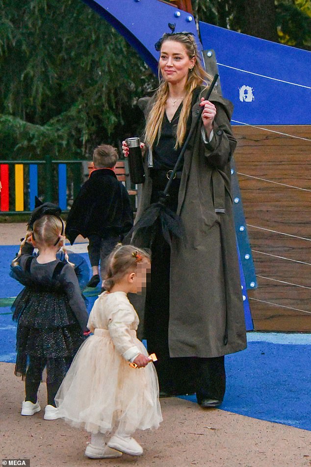 Mother-daughter outing: For their daytime outing, Heard dressed in an all-black outfit and a gray cozy trench coat to complement her only child's sparkly witch costume.  To celebrate the holiday with her daughter, she wore a wrap blouse and wide-leg velvet pants with her oft-worn black belt with a gold buckle.