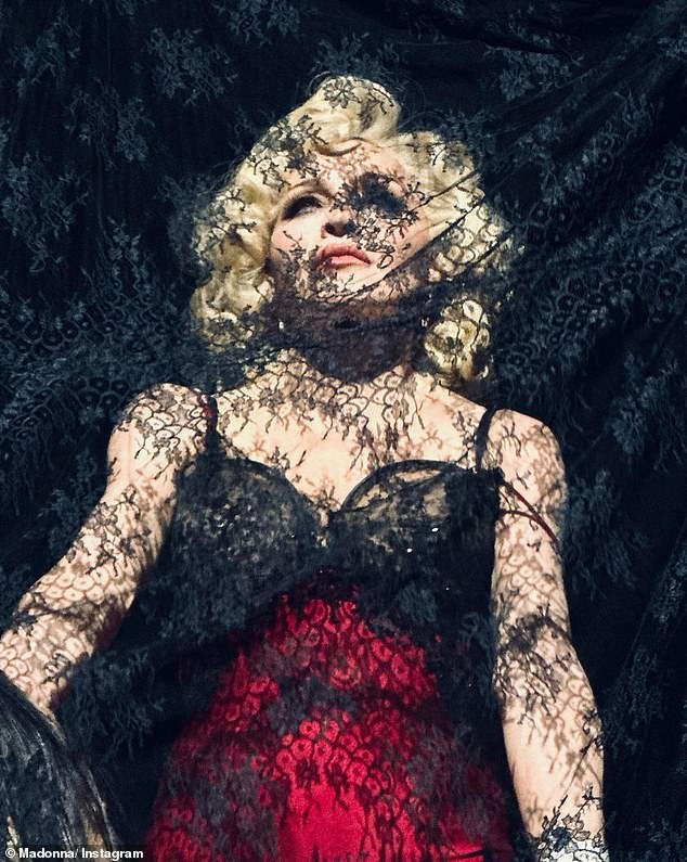 Negligee: Another onstage look showed the Vogue artist wearing a black and red negligee behind a black lace curtain.  Her blonde hair was styled in big, full curls and her makeup included a smoky eye