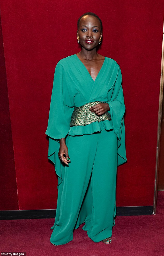 Stunning: The beauty stuns in a vibrant green blouse with a V-neck front and cap sleeves with the fabric falling to the floor behind her back