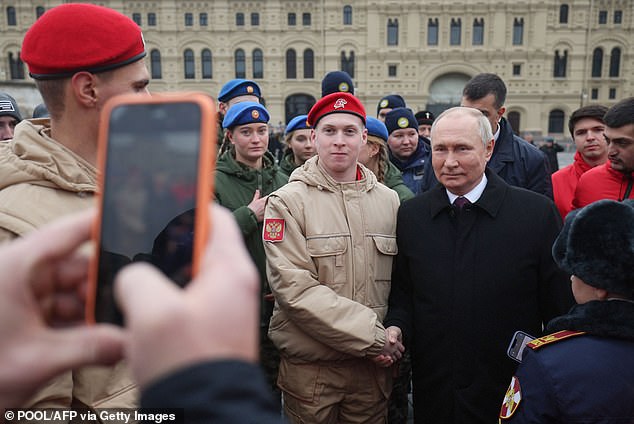 Person taking a photo of Putin posing for a photo with a young army cadet