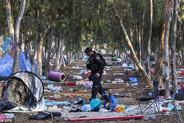 An Israeli officer walks through the grounds of the Super Nova Festival in Re'im, Israel on Tuesday.  Festival goers left their belongings behind and fled from Hamas terrorists