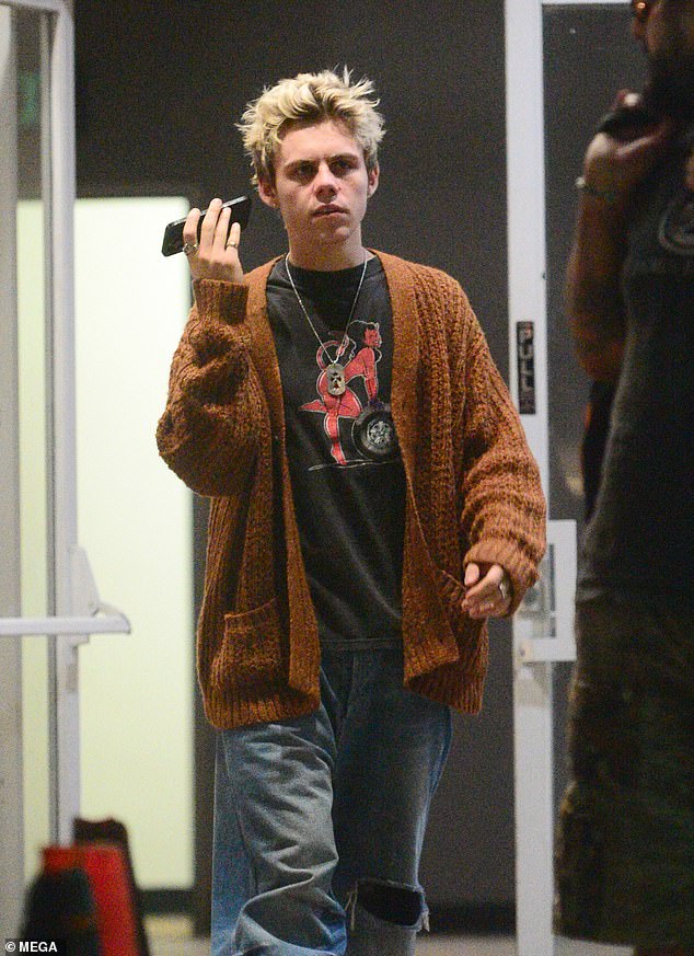 The hitmaker looked casual and wore a brown knitted cardigan, a black print T-shirt and wide ripped hoops, complete with a necklace and brushed sneakers.