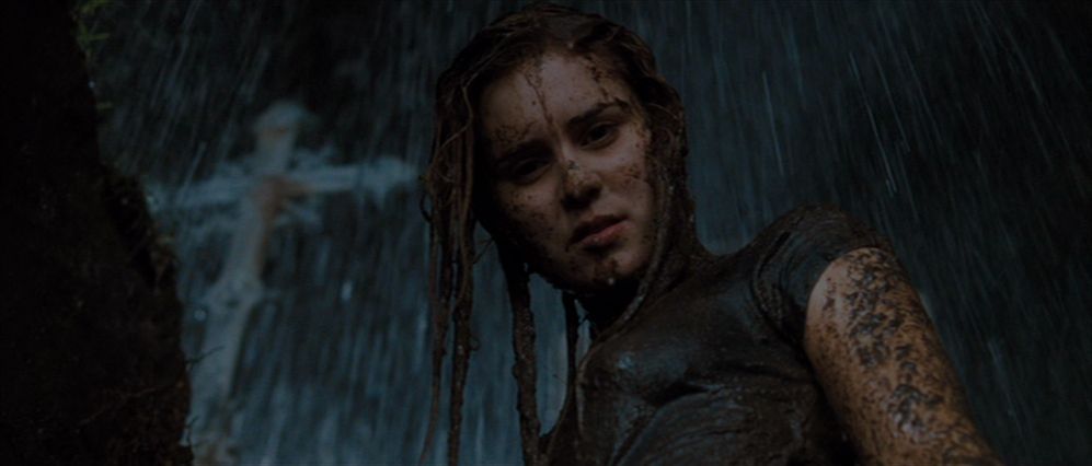 Alison Lohman as Christine Brown standing in an open grave with a cross visible in the background, drenched in mud and rainwater in Drag Me to Hell.