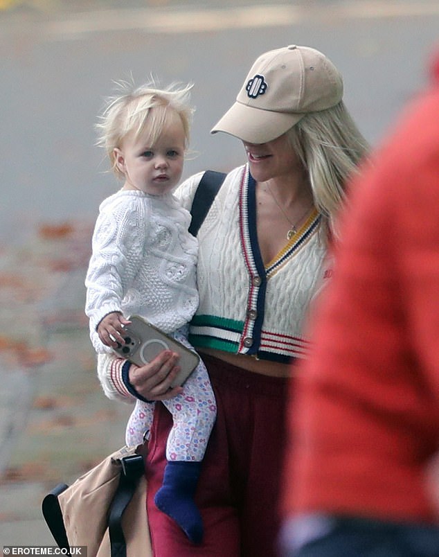 Sweet: The TV personality smiled in a casual ensemble as she cradled Bodhi, 15 months, on her hip