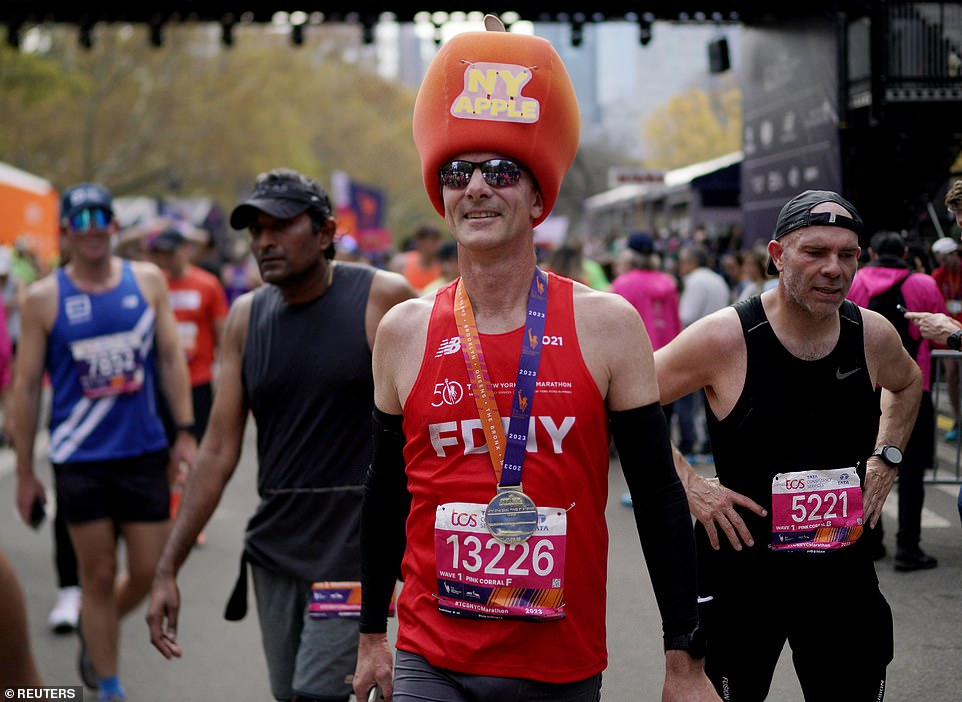 A runner wore an apple on his head to protect his ears from the cold fall weather in New York as he smiled after crossing the finish line