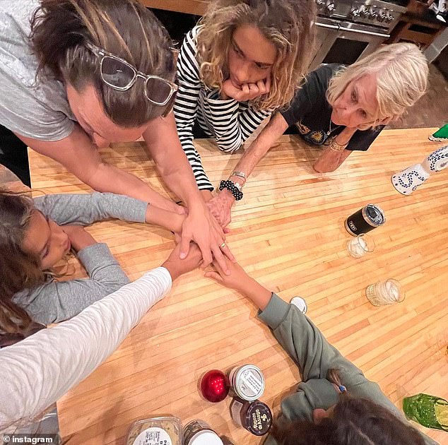 Family fun: In the final photo, the family sat around a kitchen table, their hands intertwined in a heartwarming moment