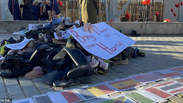 A collection of shoes was scattered on the floor, next to a poster that read 'Bring them home'