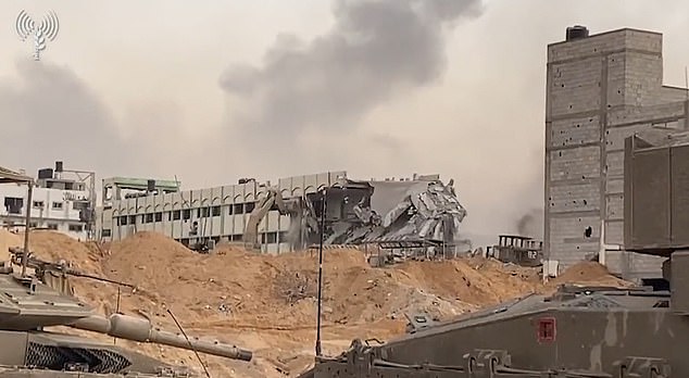 A demolition machine is seen demolishing a building partially destroyed by Israeli tanks