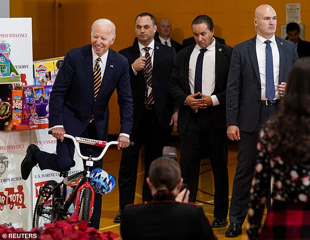 Members of US President Joe Biden's security detail stand by as President Biden pretends to ride a bicycle in December last year