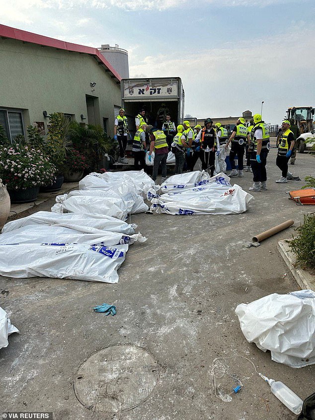 Emergency personnel stand next to body bags kept outside a building following the October 7 Hamas attack in Kibbutz Alumim, Israel, in this social media image released on November 6.  Israel says more than 1,400 people have been killed in the country, most of them civilians, in the Oct. 7 Hamas raid that started the war