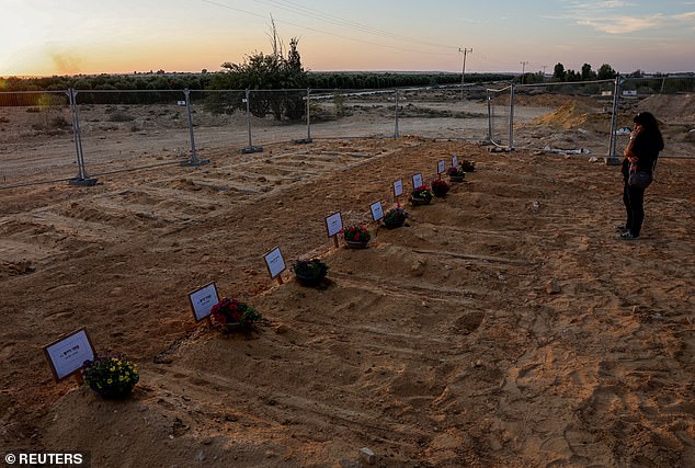 A woman looks at newly dug graves for the victims of the October 7 attack during the funeral of Albert Miles, 80, who was killed in his home in Kibbutz Beeri during the deadly infiltration of Israel by Hamas gunmen from the Gaza Strip, on the cemetery in Kibbutz Revivim, October 30