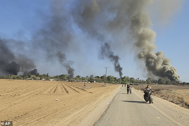 Smoke rises as Palestinians drive away from the Israeli kibbutz Kfar Aza on October 7