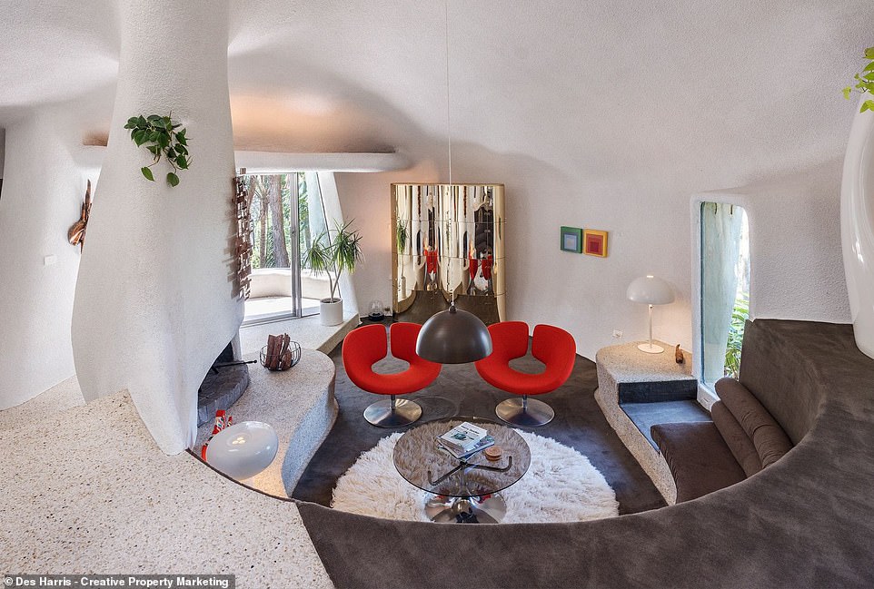 A terrace leads to the front door where guests are greeted with a foyer and a mid-century modern living room with a sunken sitting den and wavy fireplace