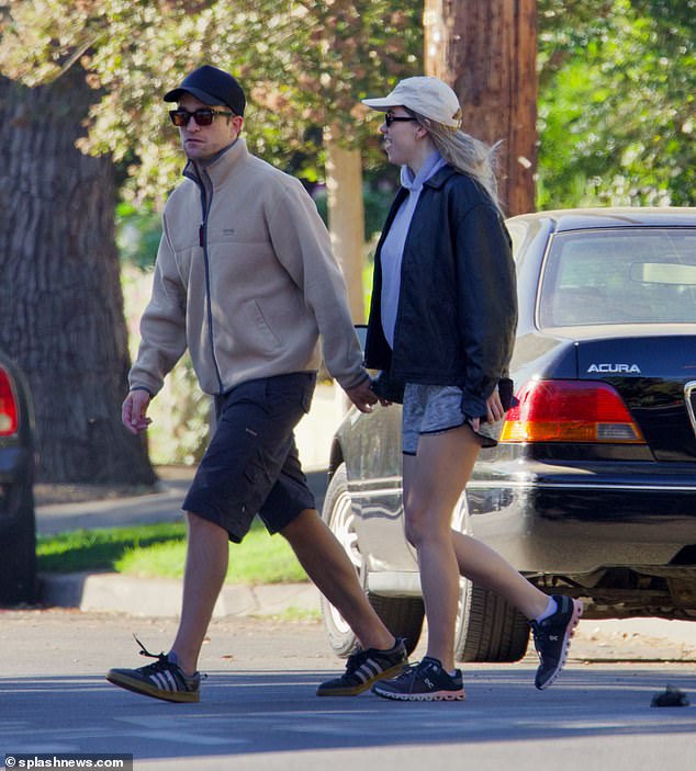 Casual couple: Suki completed the casual look with a light brown baseball cap, while her famous boyfriend followed suit with a light jacket, shorts and a hat