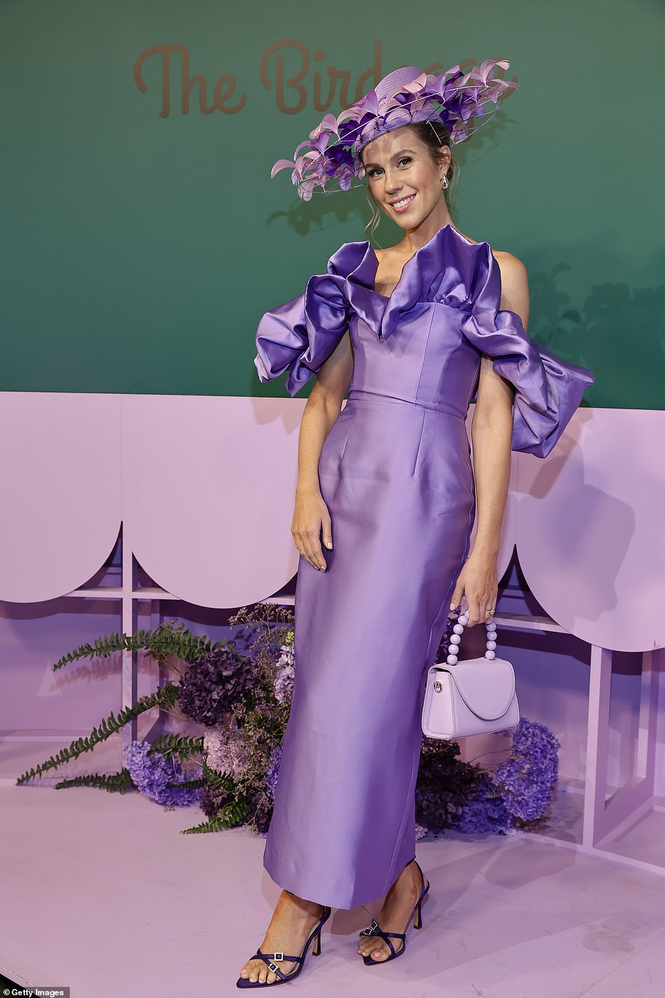 Racing socialite Crystal Kimber embraced the purple dress code by wearing a purple satin gown with ruffles, paired with a feather-adorned hatinator and eggplant heels