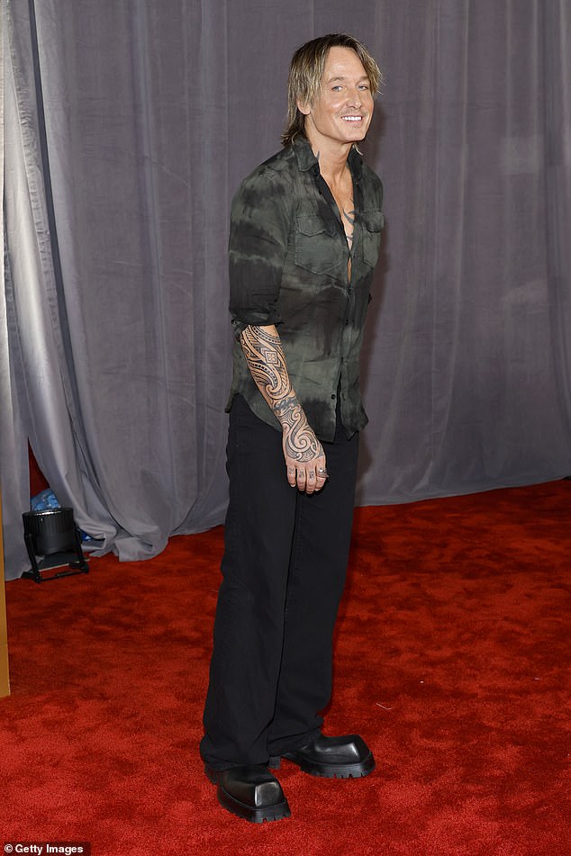 Stylish: The singer wore a dark green button-up that was partially undone at the collar, as well as black pants