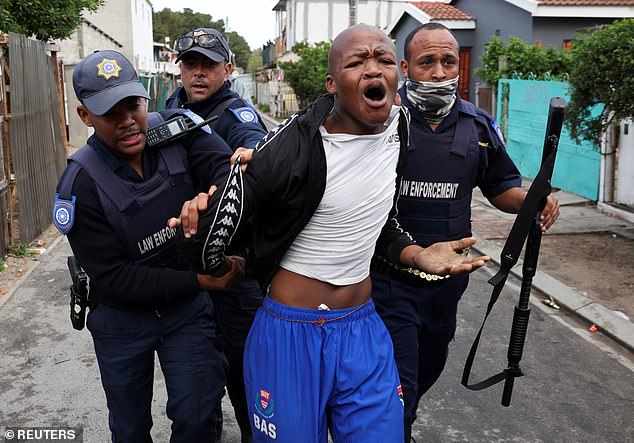 Law enforcement officers detain a protester during an ongoing strike by taxi companies against traffic authorities in Msiphumelele, Cape Town, South Africa, August 8