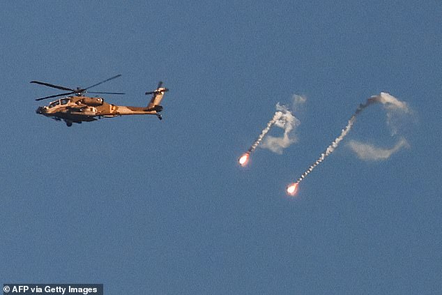 An Israeli Air Force attack helicopter fires flares as it flies over the Gaza Strip border near southern Israel on November 8, 2023