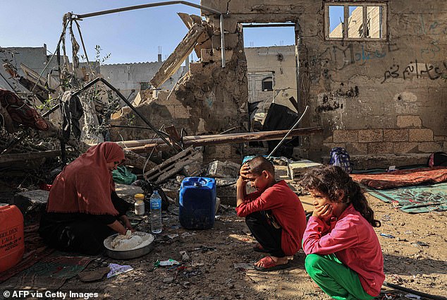 A family squats in the ruins of their home that was destroyed during an Israeli airstrike in the southern Gaza city of Rafah