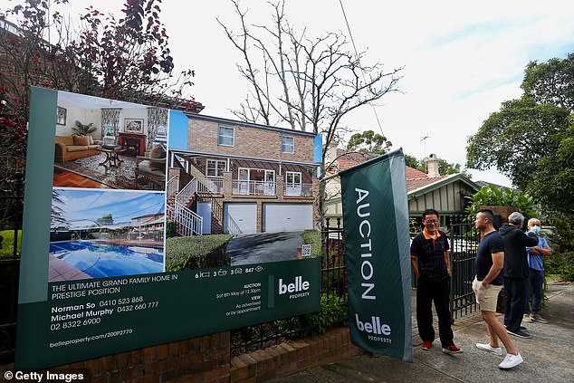 Rising inflation means workers are facing a reduction in real wages, while the Reserve Bank's 13 rate hikes in 18 months have eroded the savings of those with mortgages (pictured at an auction in Sydney)