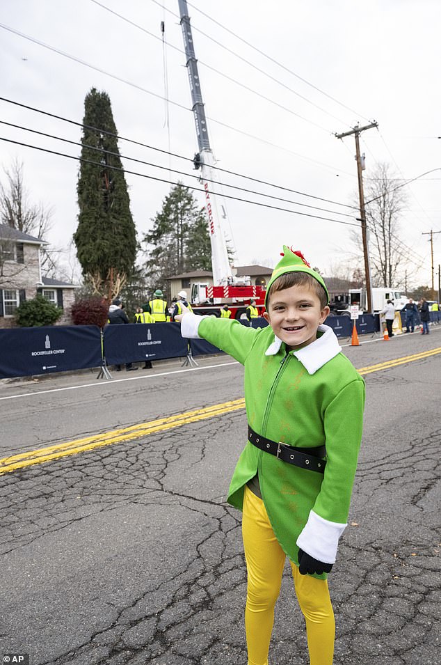 Noah McElligott, 10, poses near the wrapped 80-foot Norway spruce that will serve as this year's Rockefeller Center Christmas tree