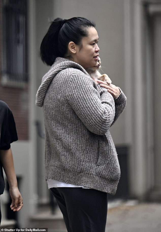 Chen, 45, was handed a puppy as she walked outside, before cradling the pooch in her sweater to keep warm