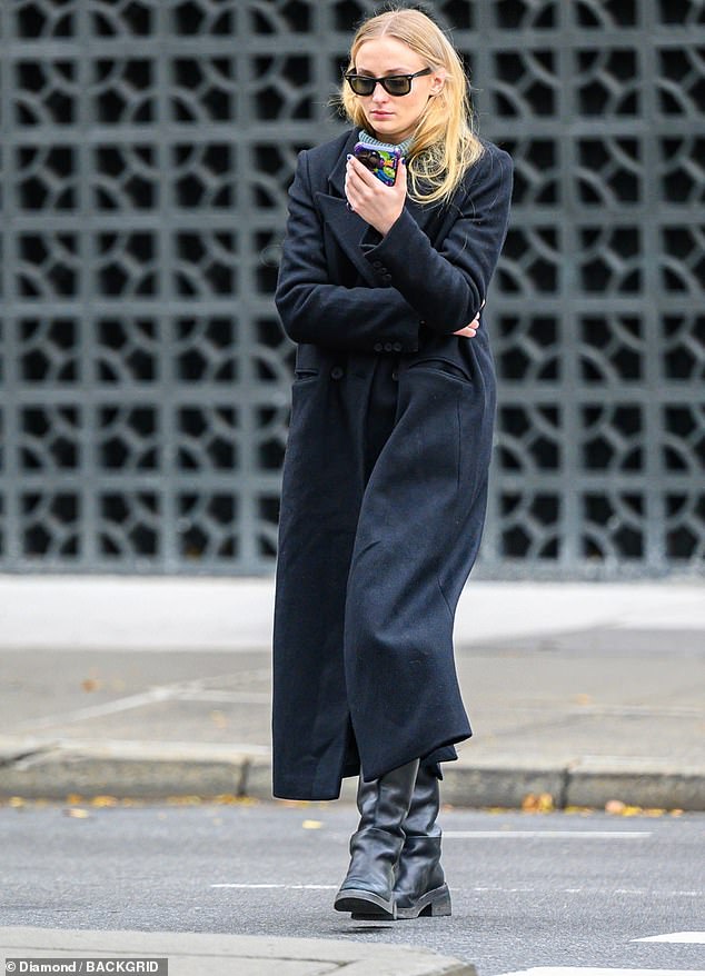 Cozy coat: The Game of Thrones alum, 27, bundled up in a long, cozy-looking black coat and black boots