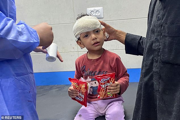 Palestinian girl Orheen Al-Dayah, who was wounded in the forehead during an Israeli attack amid the ongoing conflict between Hamas and Israel, is helped after her wounds were stitched without anesthesia at Al Shifa Hospital