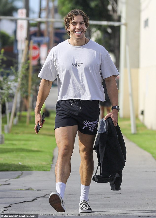 Ready for the day: The bodybuilder was seen with a smile on his face as he donned a white Gold's Gym short-sleeved shirt and black gym shorts