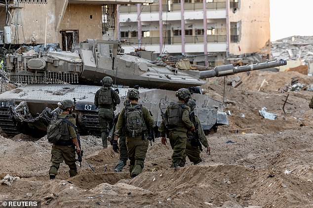 Israeli soldiers walk through the rubble amid the ongoing ground invasion against Palestinian Islamist group Hamas in the northern Gaza Strip on Wednesday