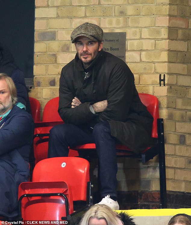 Stylish: He completed his look with a Barbour wash jacket and dark blue jeans as he took his seat in the stands