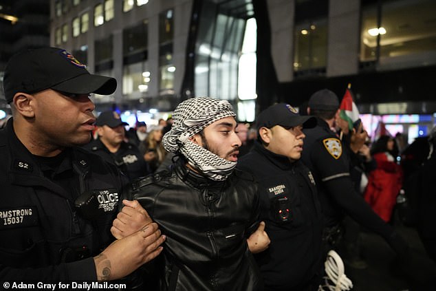 The protester is seen being led away outside Grand Central on Friday evening