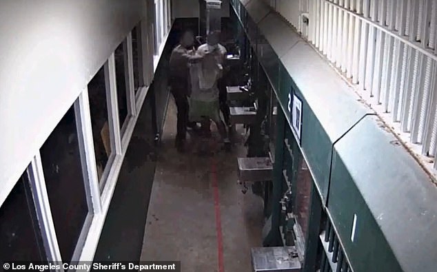 Here a prisoner, with his hands behind him, is seen being grabbed by two officers after leaving his cell