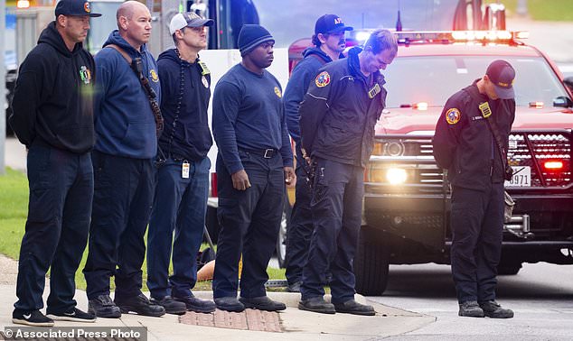 Members of the Austin Fire Department bow their heads as they prepare to ride in procession with the fallen office