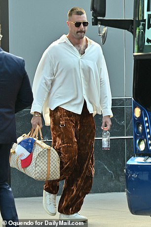 Kelce wears a white button-down with brown pants and cream sneakers