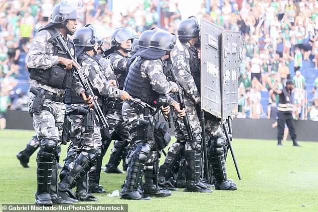 Police and security personnel enter the field to try to restore order among the fans