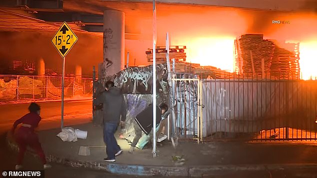 A homeless camp under an overpass was forced to evacuate as flames spread