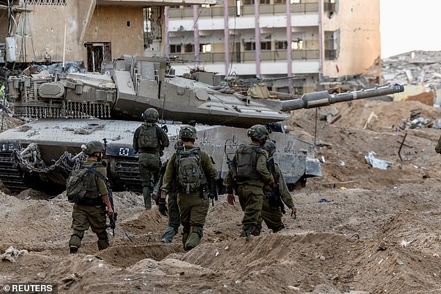 Israeli soldiers walk through rubble amid the ground invasion against Palestinian Islamist group Hamas in the northern Gaza Strip, November 8, 2023