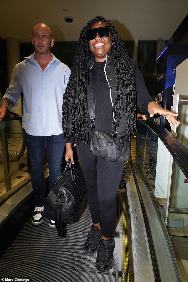 Looking good: She looked relaxed as she carried her bags, dressing for comfort in a stretchy black jumpsuit and matching trainers