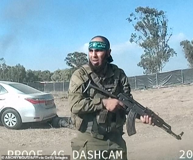 Pictured: An armed Palestinian militant walks around the Supernova music festival near Kibbutz Reim in the Negev Desert in southern Israel on October 7