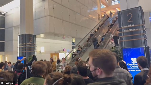 Dozens of peace activists sat on the steps of the Accenture Tower escalators Monday morning, blocking people from going up to work