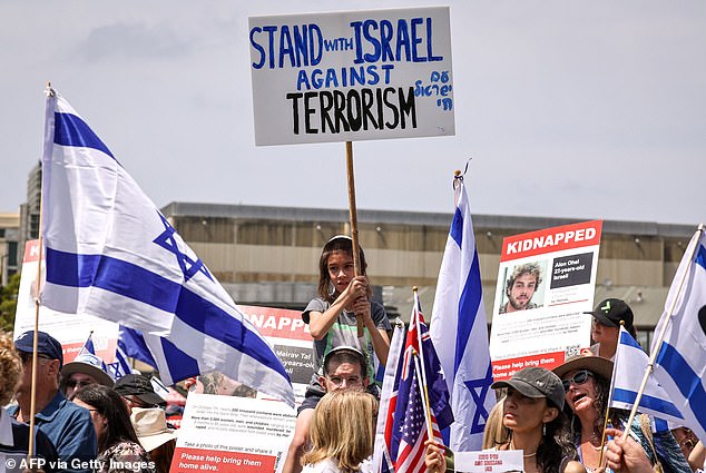 It is understood NSW has spoken to Victoria about approaching the Federal Government in a united front for help managing protest costs (Members of the Australian Jewish community hold signs and flags at a rally in Sydney on November 12)