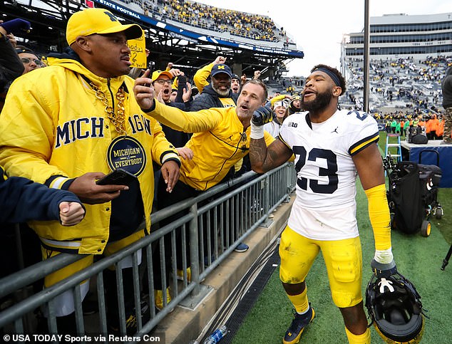 Linebacker Michael Barrett celebrates with a fan wearing a 'Michigan vs Everybody' necklace